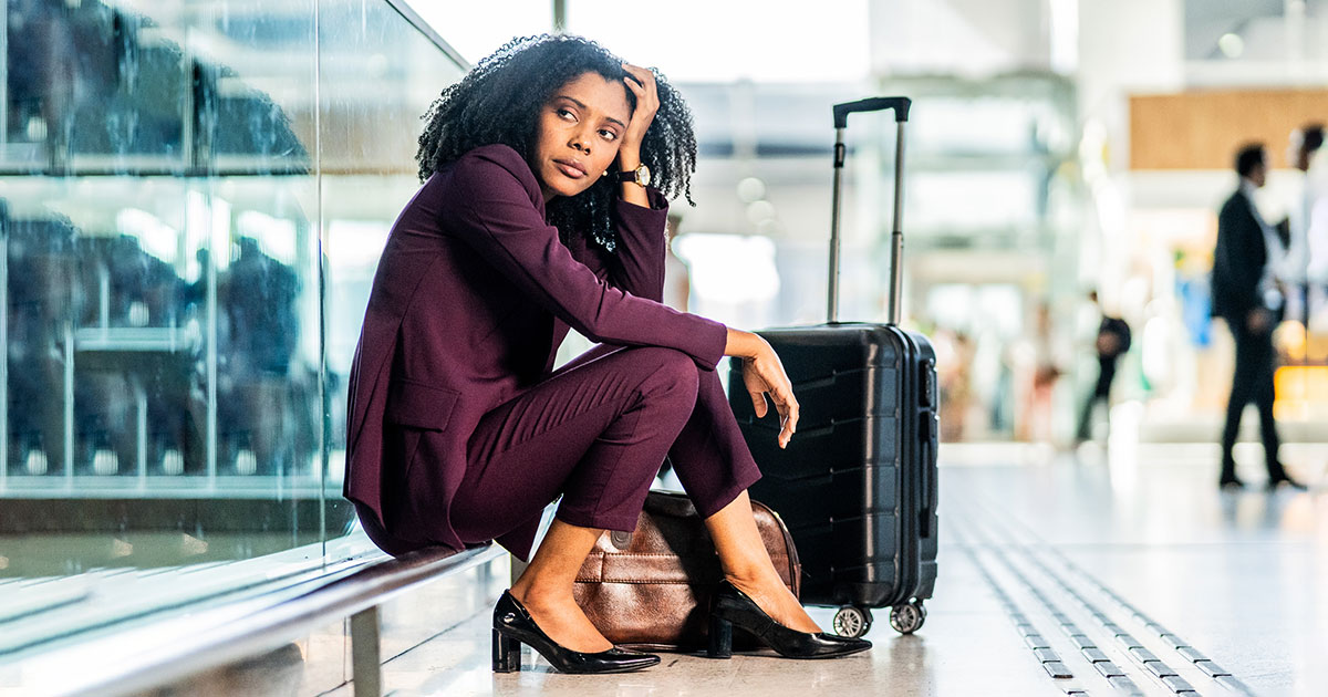 business woman sits in an airport looking frustrated