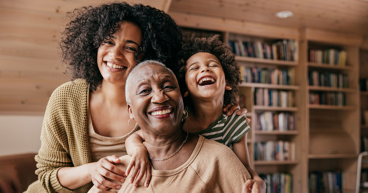 three generations of women smile at the camera