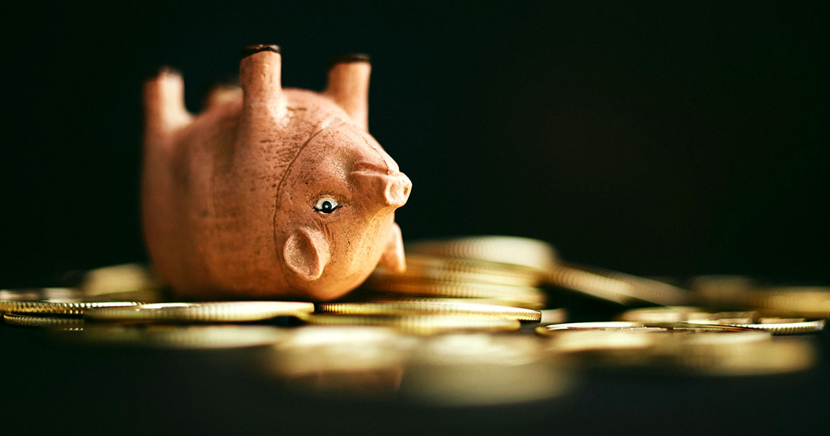 piggybank upside-down with coins all around