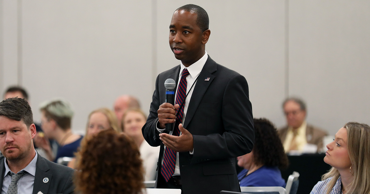 William Harris stands as he speaks into a microphone