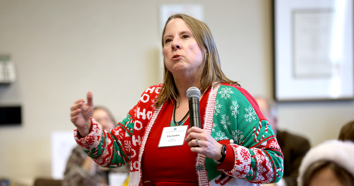 Lisa Lawless stands and holds a microphone