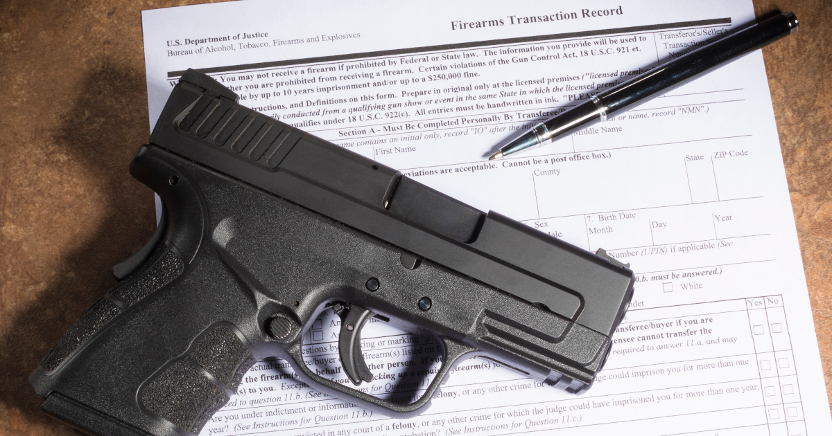 A Black Automatic Pistol And Ballpoint Pen Lie Atop A Federal Fire Arms Transaction Form On A Countertop