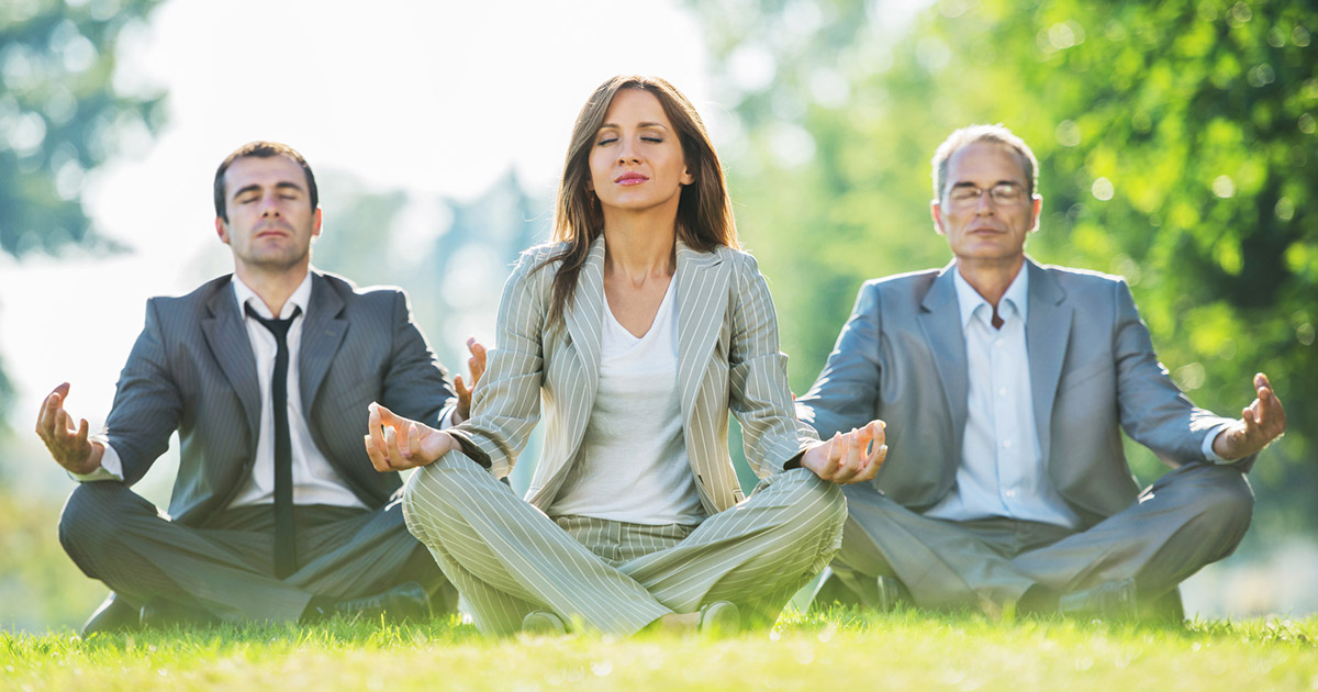 stock photo of three people meditating in a park