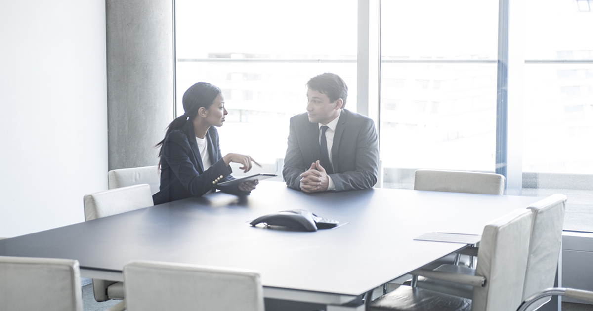 stock photo of two people talking at a table in an office