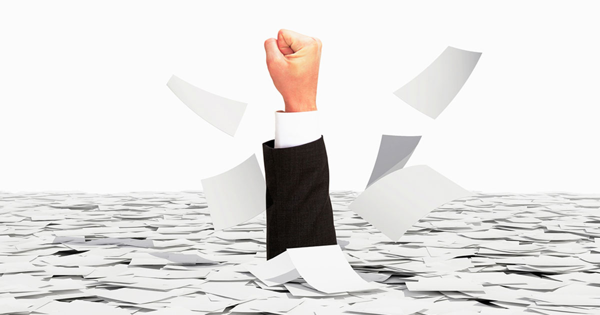 stock photo showing a human first emerging from a large pile of paperwork