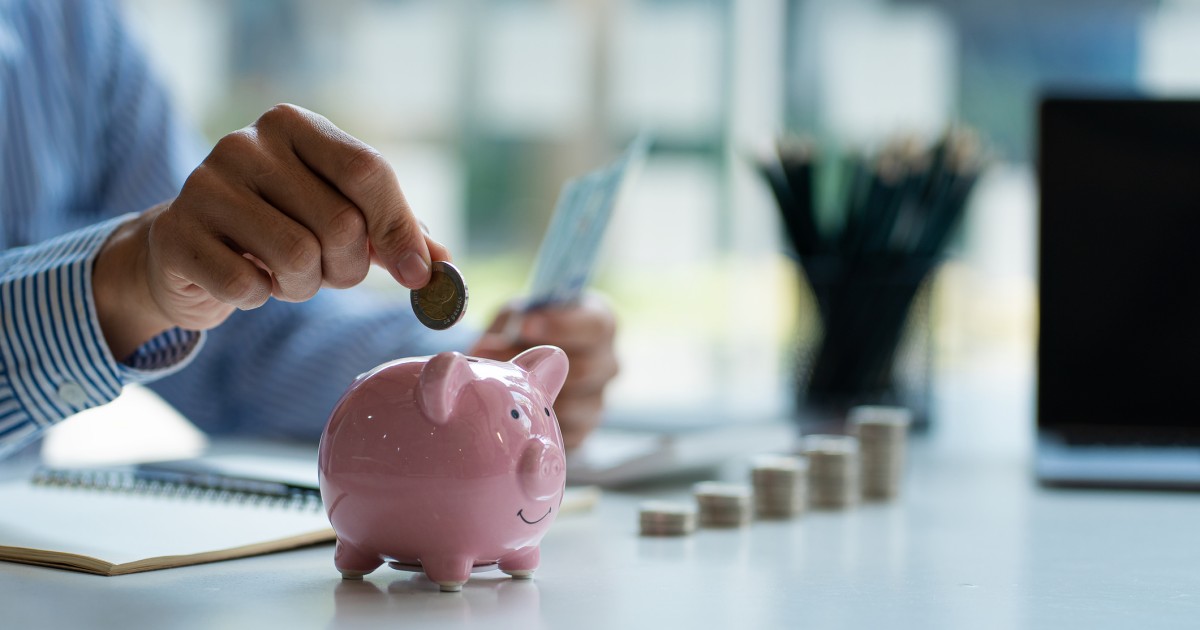 A coin being placed into a piggy bank