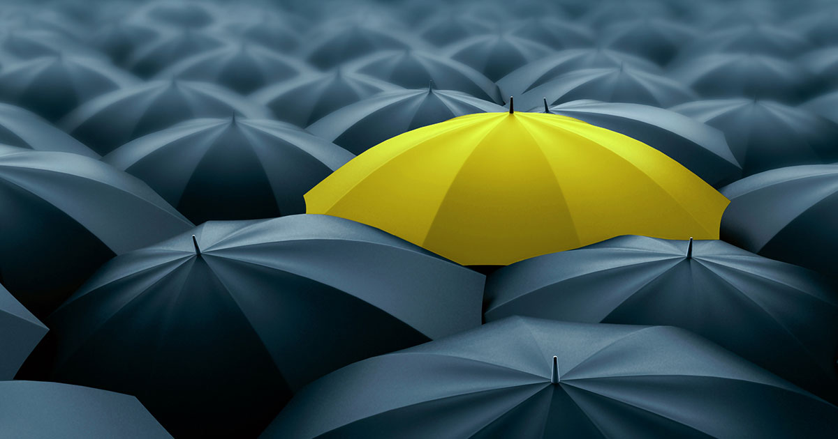 yellow umbrella in sea of black umbrellas