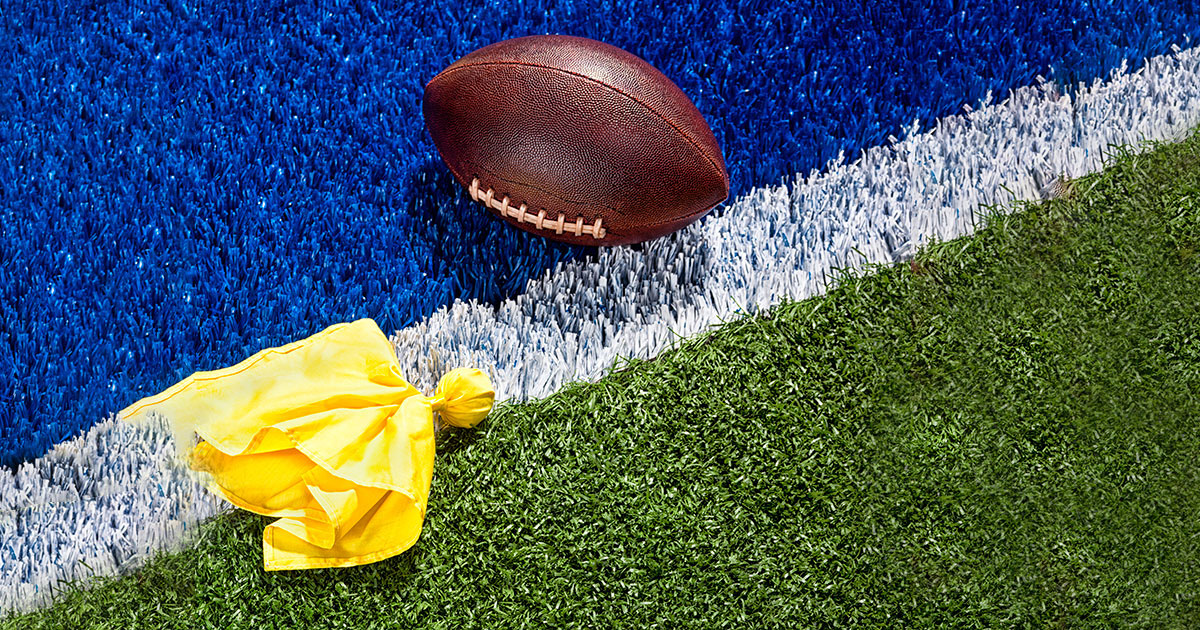 football on field with penalty flag nearby