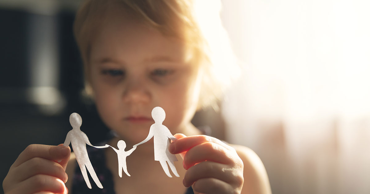 girl playing with paper cut out of family